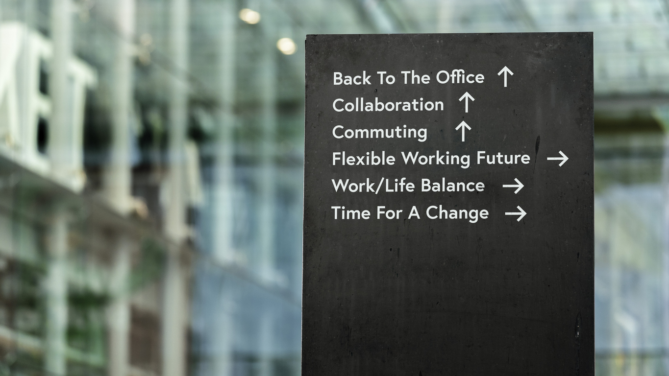 Working future choices on a black city-center sign in front of a modern office building