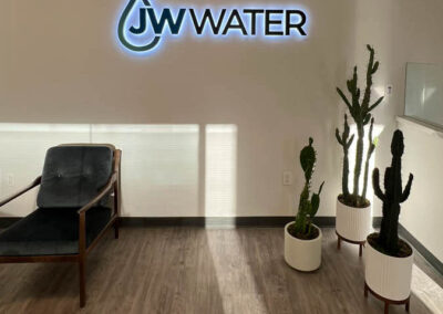 JW Water signage in an office with cactus plants and modern chair. Custom sign by Arizona Custom Signworks. Phoenix signage solutions.