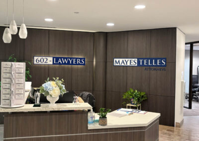 Reception area of a Phoenix law firm featuring wood paneling, 602-LAWYERS and Mayes Telles Attorneys signs by Arizona Custom Signworks.