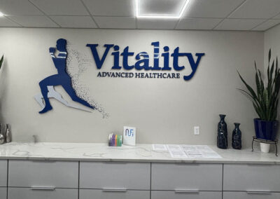 Arizona Custom Signworks crafted Vitality Advanced Healthcare sign in Phoenix office, featuring blue lettering and a dynamic runner silhouette.