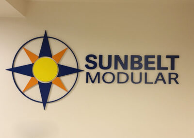 Sunbelt Modular wall sign with a compass logo, crafted by Arizona Custom Signworks, Phoenix. Blue lettering and vibrant color details.