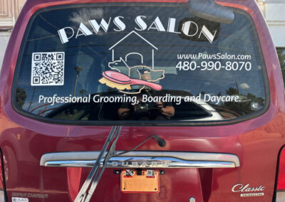 Red Subaru with Paws Salon rear window decal featuring QR code, contact info, and services. Captured in Phoenix area, Arizona Custom Signworks.