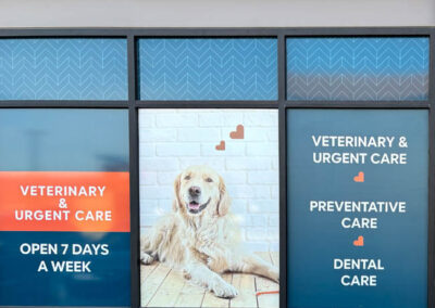 Veterinary clinic window signage by Arizona Custom Signworks, Phoenix. Ad features dog with services: urgent, preventative, dental care. Open daily.